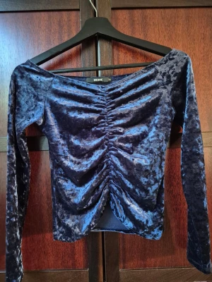 Mörkblå sammetstopp - En mörkblå långärmad topp i mjuk sammet från Bik Bok. Toppen har smickrande offshoulder-modell och snygg rynkning framtill som ger en snygg look. Perfekt att styla med jeans eller kjol för en utekväll.