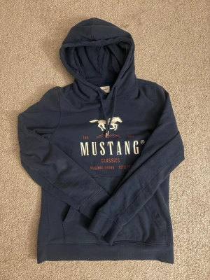 Mustang Hoodie - En mörkblå mustang hoodie i strl S. Har en nice passform och sitter skönt. Säljer då den var för liten för mig. Helt ny förutom att ja använde de. 1 gång till skolan.