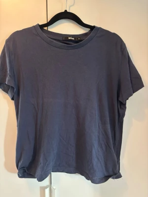 Mörkblå t-shirt från Bik Bok - En enkel och stilren mörkblå t-shirt från Bik Bok i mjuk bomull. T-shirten har rund halsringning och korta ärmar, perfekt till alla dina outfits. Passformen är normal och tyget känns skönt mot huden.