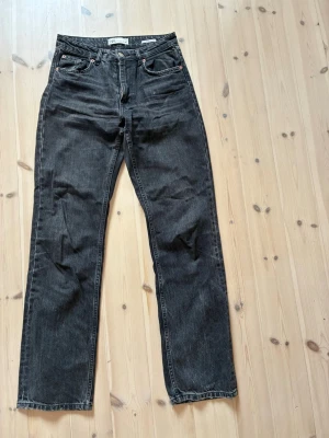 Svarta raka jeans från Zara - Säljer ett par svarta raka jeans från Zara i storlek 36. Jeansen har klassisk femficksmodell, hög midja och dragkedjegylf. Materialet är denim i bomull med en lätt tvättad look. Perfekta för en avslappnad och trendig stil.