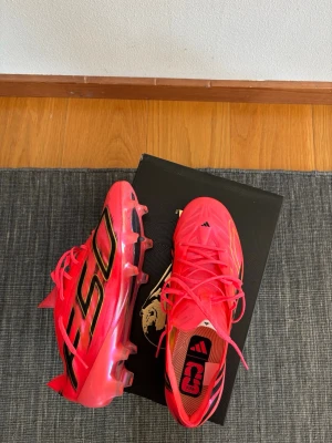 Adidas X Speedflow rosa fotbollsskor - Säljer ett par grymma Adidas X Speedflow fotbollsskor i en riktigt snygg rosa färg med svarta och guldiga detaljer. Skorna har snörning, låg profil och lätta material för maxad fart på planen. Perfekta för dig som vill sticka ut och spela snabbt!