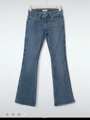 Blå bootcut jeans med utsvängda ben - Säljer ett par klassiska blå bootcut jeans med utsvängda ben och fem fickor. Jeansen har normal midja och är gjorda i ett mjukt denimtyg med lätt tvättade detaljer. Perfekta för dig som gillar retrovibbar och en avslappnad look.