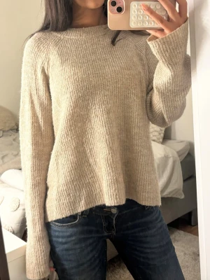 Beige oversized stickad tröja - Mysig beige stickad tröja med avslappnad passform och långa ärmar. Tröjan har rund halsringning och är tillverkad i ett mjukt, ribbstickat material som ger en chill och enkel look. Perfekt att slänga på sig till jeans eller leggings. Tröjan är i storlek XL men passar mig som har S i tröjor 