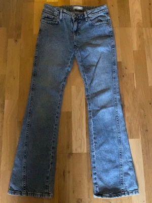 Blå low waist bootcut jeans - Säljer ett par klassiskt lågmidjade blå bootcut jeans i denim. Jeansen är använda fåtal gånger men sitter fint med bra passform. Perfekt om man vill ha neutrala jeans med något litet extra.💖