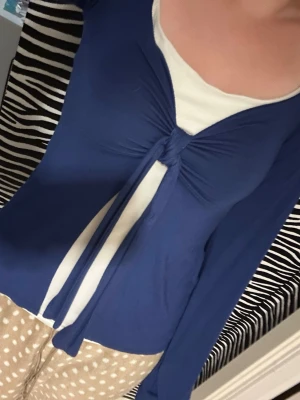 Blå långärmad topp med knyt - Snygg blå långärmad topp med v-ringning och knyt framtill. Tunn och stretchig, perfekt att styla över ett linne eller topp. Trendig modell som ger en cool och avslappnad vibe. Pris går att diskutera🌷