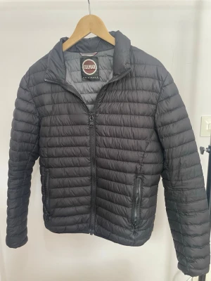 Svart pufferjacka från Colmar - Säljer en svart pufferjacka från Colmar Originals med quiltad design och dragkedja framtill. Jackan har två sidofickor med dragkedja och hög krage. Perfekt för kalla dagar och riktigt snygg till streetwear-stilen.
