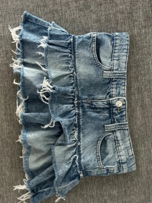 Blå jeansskort med volanger - Säljer en blå jeansskort med  volangdetaljer. 