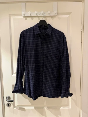 Massimo Dutti skjorta - Snygg mörkblå skjorta med rutigt mönster och klassisk krage. Skjortan har långa ärmar och knäppning framtill. Perfekt för dig som gillar en avslappnad men stilren look.