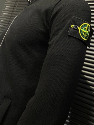 Svart zip hoodie från Stone Island - Säljer en svart hoodie från Stone Island med dragkedja framtill och ikonisk patch på vänster ärm. Hoodien har ribbade muddar, två fickor och är gjord i ett mjukt, strukturerat material. Perfekt för dig som gillar streetwear och vill ha en clean look.Finns både S och M storlek 