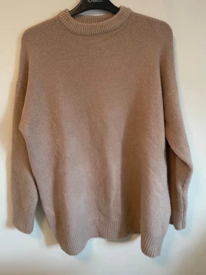 Beige stickad tröja - Mysig beige stickad tröja i modell med rund halsringning och ribbade muddar vid ärmslut och nederkant. Perfekt för lager på lager och enkel att matcha med olika stilar. Materialet känns mjukt och skönt mot huden.