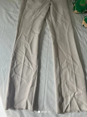 Beiga kostymbyxor från BikBok - Snygga beiga kostymbyxor från BikBok i rak modell med pressveck och hällor för skärp. Byxorna har en stilren look och är tillverkade i ett mjukt, vävt material som känns bekvämt. Perfekta att styla med en crop top eller oversized skjorta.