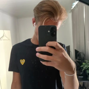 Svart Comme des Garçons t-shirt hjärta - Svart t-shirt från Comme des Garçons Play med det ikoniska gula hjärtat med ögon broderat på bröstet. Klassisk passform, rund hals och korta ärmar. Tillverkad i mjuk bomull som är skön mot huden. Perfekt för dig som gillar stilrena plagg med en twist. Storlek L men sitter mer som en M/S. Pris kan diskuteras vid en snabb affär.