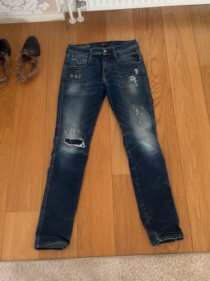 Mörkblå slitna skinny jeans - Säljer ett par mörkblå skinny jeans med slitningar och hål på benen. Jeansen har fem fickor, låg midja och snygga slitdetaljer framtill. Materialet är klassisk denim med stretch för skön passform. Perfekta för en avslappnad och trendig look.