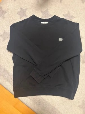 Svart sweatshirt från Stone Island - Säljer en svart sweatshirt från Stone Island med klassisk rund hals och logotyp-patch på bröstet. 