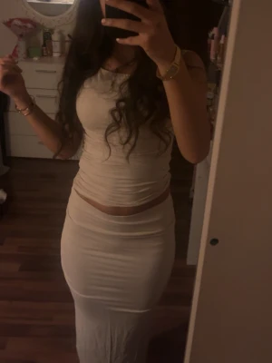 Beige two piece - Säljer en lång, vit kjol med tight passform. Kjolen är enkel och stilren utan mönster, perfekt för dig som gillar minimalistisk stil Tillhörande topp