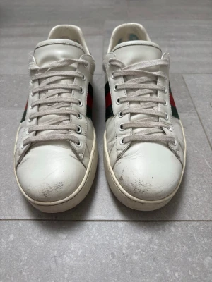 Vita gucci ace - Vita gucci ace använda några gånger. Skora i sig är i bra skick, de ända är lite på framsidan och lite bland hälarna. Skorna är köpta från vestiaire för 3799kr. Skorna är i storlek 44 men passar även 45. Skriv frågor vid funderingar! Priset är inte hugget i sten🚨