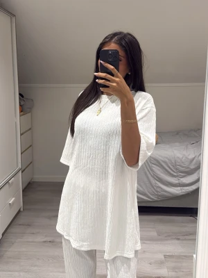 Vitt ribbat loungewear-set - Säljer ett vitt loungewear-set med ribbad struktur. Setet består av en oversized t-shirt med rund hals och korta ärmar samt matchande byxor med resår i midjan. Perfekt för chill dagar hemma eller när du vill vara bekväm men ändå snygg.