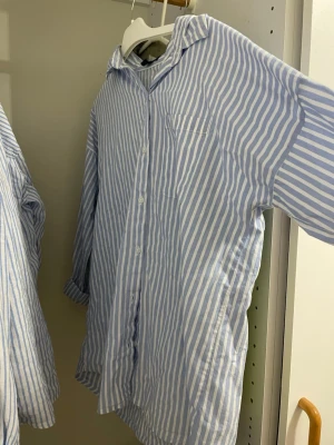 Blåvit randig skjorta från Boohoo - Säljer en blåvit randig skjorta från Boohoo i storlek 36. Skjortan har klassisk krage, knäppning framtill och en bröstficka. Tillverkad i ett lätt och skönt material, perfekt för en avslappnad och stilren look.