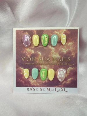 Lolli (XS);ExtraShortAlmond  - Handgjorda press-on nails i en lekfull mix av gult, grönt, mint och lila. Setet har skimrande detaljer, prickar och handmålade fiskmotiv som ger en färgstark och annorlunda look.  Form: Extra Short Almond Storlek: XS 10 naglar ingår