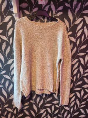 Beige stickad tröja med lös passform - Mysig beige stickad tröja med rund halsringning och lång ärm. Tröjan har en lös och avslappnad passform samt ribbstickade kanter vid hals, ärmslut och nederkant. Perfekt för lager på lager och chill dagar.