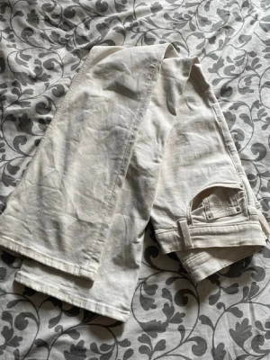 Vita  jeans med fickor - Säljer ett par vita jeans med klassiska fem fickor. Jeansen har bälteshällor och knappgylf. Materialet är denim i bomull och de har en stilren look som passar till det mesta. Perfekta för dig som vill ha ett par ljusa jeans i garderoben.