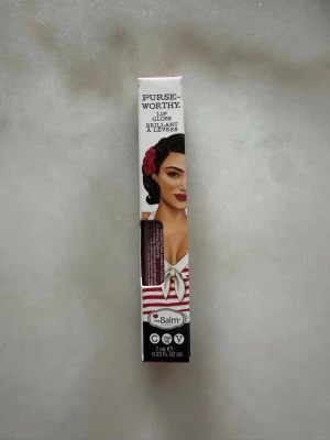 theBalm Clutch Lipgloss röd - Säljer ett läppglans från theBalm i nyansen Clutch. Färgen är en djup röd med glansig finish. Förpackningen är dekorerad med retroinspirerad design och innehåller 7 ml. Perfekt för dig som vill ha ett glossigt resultat med färg. Oöppnad förpackning.