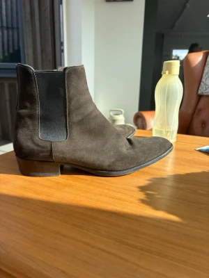 Saint Laurent Wyatt 30 boots - Mörkbrun mocka, storlek EU45. Väldigt fint begagnat skick, främst normalt slitage på sulorna. Inga större defekter på ovandelen.  Tillverkade i Italien. Nypris för motsvarande modell ca 12 000 kr.