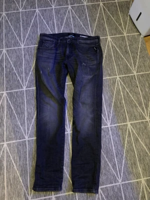 Mörkblå jeans från Replay - Säljer ett par mörkblå jeans från Replay Sustainable Lab med klassisk femficksdesign och raka ben. Jeansen har subtila slitningar framtill och är tillverkade i denim med snygg tvätt. Perfekt för dig som vill ha en stilren och modern look. KÖPTES HELT NYA FRÅN JOHNELSS FÖR 1999 KNAPPT ANVÄNDA KVITTO FINNS PÅSE MEDFÖLJER KÖPTET JENASEN ÄR SOM SAGT HELT NYA KNAPPT ANVÄNDA  FPÅOR SKRIV 