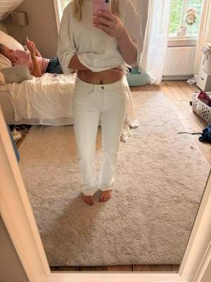 Vita raka jeans med hög midja - Säljer ett par vita jeans med rak passform och hög midja. Jeansen har klassisk femficksdesign och stängs med dragkedja och knapp. Perfekta för dig som vill ha en clean och fräsch look till sommaren.