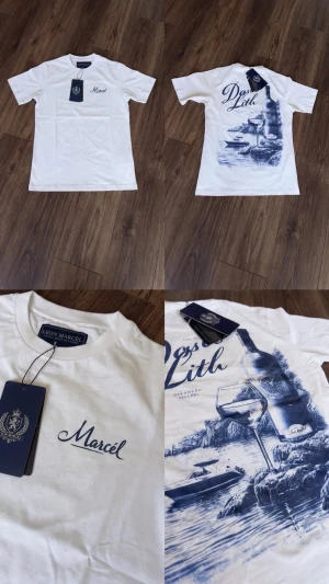 Vit t-shirt från Léon Marcel - Vit t-shirt från Léon Marcel med tryck fram och bak. Framsidan har diskret texten 'Marcel' och baksidan har ett stort blått motiv med vinflaska, glas och landskap. Klassisk passform och rund hals. Perfekt för en chill och stilren look.