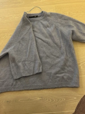 Ljus blå stickad tröja - Mysig ljus blå stickad tröja med rund halsringning med korta armar. Tröjan har ribbstickade muddar vid ärmslut och nederkant. Perfekt för kyliga dagar och enkel att matcha med olika outfits. Sitter som en s