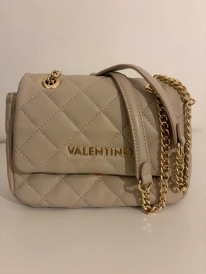 Beige quiltad handväska Valentino - Snygg beige handväska från Valentino med quiltat mönster och guldfärgade detaljer. Använd ett få tal gånger och köpt på zalando för 1345kr