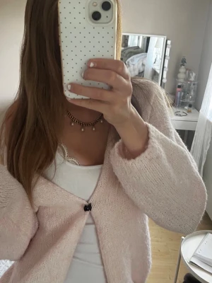 Ljusrosa fluffig kofta - Mysig ljusrosa kofta med fluffig känsla och v-ringning. Koftan har en enkel knapp framtill och avslappnad passform med långa ärmar. Perfekt att slänga över ett linne för en chill look.