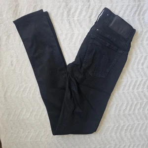 Svarta skinny jeans från Tiger of sweden  - Säljer ett par svarta skinny jeans från T/J med klassisk femficksdesign och läderpatch bak i midjan. Jeansen har smal passform och är tillverkade i stretchigt denimtyg som sitter snyggt. Perfekta för en clean och stilren look.