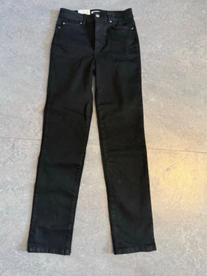 Svarta skinny jeans med hög midja -  svarta skinny jeans med hög midja och klassisk femficksdesign. Jeansen har smal passform och raka ben, perfekta till en trendig vardagslook. Materialet är stretchigt denim för extra komfort.