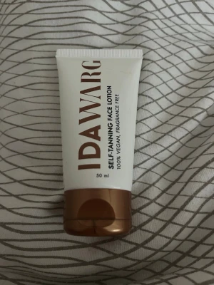 IDA WARG Self-Tanning Face Lotion - Brun utan sol-ansiktskräm från IDA WARG. Tuben innehåller 50 ml och är 100% vegansk samt parfymfri. Förpackningen är vit med bronsfärgat lock och text i brons.  Använd 2 gånger har ca 40- 35 ml kvar. 