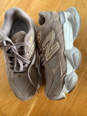Beige New Balance sneakers - Snygga beige sneakers från New Balance med klassisk N-logga på sidan. Skorna har en chunky sula, ovandel i mocka och mesh samt matchande skosnören. Perfekta för dig som gillar streetwear och vill ha bekväma skor med retrovibbar. Använt en gång bara 