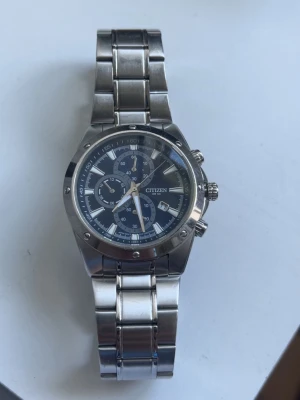 Citizen silverfärgad kronografklocka - Stilren kronografklocka från Citizen i silverfärgat stål. Klockan har blå urtavla med flera små urtavlor, datumvisning och robust länkarmband. Perfekt accessoar för dig som gillar klassisk och sportig stil.