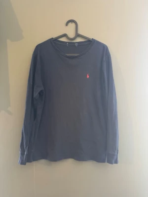 Mörkblå långärmad tröja Polo Ralph Lauren - Mörkblå långärmad tröja från Polo Ralph Lauren med rund halsringning och den klassiska röda logotypen broderad på bröstet. Tillverkad i mjuk bomull som känns skön mot huden. Perfekt för en avslappnad och stilren look. Som ni ser så saknar tröjan en lapp där ser står vilken storlek det är men det är st small. Hör av er vid minsta fråga och priser👌 obs priset kan gå ner mycket✅