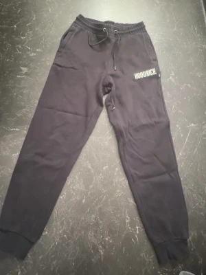 Hoodrich svarta sweatpants/joggers - Säljer ett par svarta Hoodrich sweatpants/joggers i storlek XS. Byxorna har resår i midjan med dragsko, muddar vid bensluten och Hoodrich-logga tryckt på vänster sida. Mjuka och bekväma, perfekta för vardag eller träning. Använda men i fint skick!
