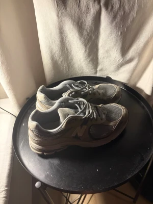 Grå New Balance sneakers - Säljer ett par klassiska grå sneakers från New Balance med meshpaneler och syntetdetaljer. Skorna har snörning och den ikoniska N-loggan på sidan. Perfekta för dig som gillar en sportig och clean stil.
