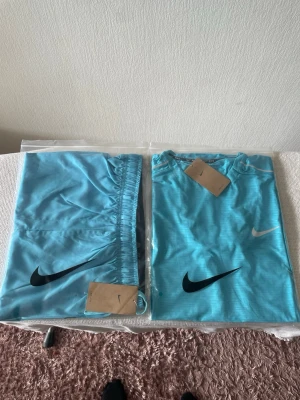 Nike Miller - Snygg turkos sporttröja från Nike med klassisk logga på bröstet. Tröjan har rund hals och är tillverkad i ett lätt, snabbtorkande material som passar perfekt till träning eller löpning.