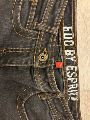Svarta jeans från EDC by Esprit - Säljer ett par svarta jeans från EDC by Esprit med raka ben och snygga kontrastsömmar i fickorna bak. Jeansen säljs då de är för små för mig! Strl: 152