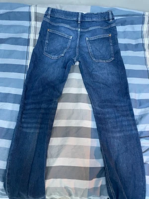 Slim fit jeans - Säljer ett par klassiska blå jeans med raka ben och två bakfickor. Jeansen har normal midja och bälteshällor. Materialet är denim i bomull och de har en tidlös look som passar till det mesta.