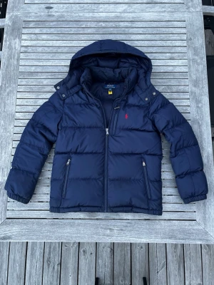 Polo ramp lauren jacka  - Hej! Säljer denna feta mörkblå polo Ralph lauren jacka som e perfekt för vintern. Den är varsamt använd i nästan 2 vintrar. Jack har inga hål eller skador, det ända är att hängbandet gått av och att den stora lappen har börjat lossna (bild 5) Annars helt perfekt. Hör av dig vid intresse!!