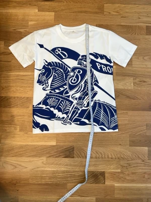 Vit t-shirt med blått riddarmotiv - Sitter lite slim fit skulle jag säga😁