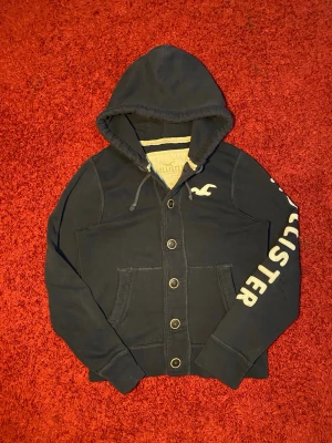 Hollister huvtröja  - Hollister huvtröja i storlek M. Sliten på ena armbågen med ett litet hål, se sista bild. Mått: axelbredd - 40 cm, armhåla till armhåla - 49 cm, längd - 57 cm. Skriv för fler bilder och frågor!