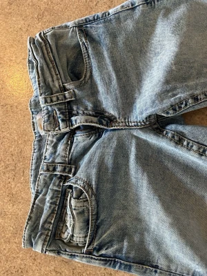 Ljusblå bootcut jeans - Säljer ett par ljusblå jeans med bootcut passform och klassiska fem fickor. Jeansen har normal midja och är tillverkade i denim med lätt tvättad look. Perfekta för en avslappnad och trendig stil.