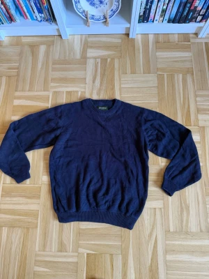 Mörkblå stickad tröja - En enkel och stilren mörkblå stickad tröja med rund hals och ribbade muddar vid ärmslut och nederkant. Perfekt för lager-på-lager och passar till det mesta i garderoben.
