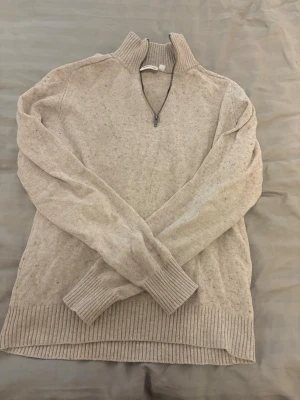 Beige stickad tröja Half zip - Mysig beige stickad tröja med hög krage och halv dragkedja framtill. Tröjan har långa ärmar och breda ribbade muddar vid ärmslut och nederkant från Kappahl 